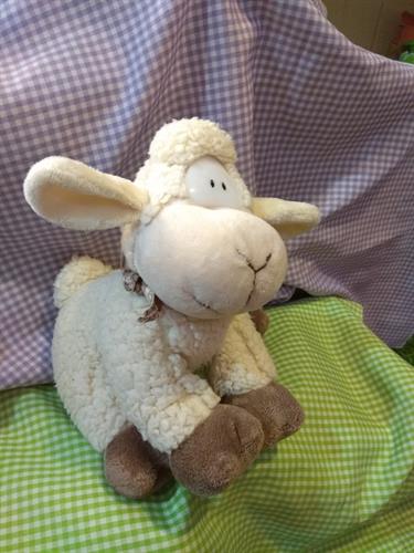 בובה רכה של כבשה צמרירית עם מטפחת קישוט סביב הצוואר.