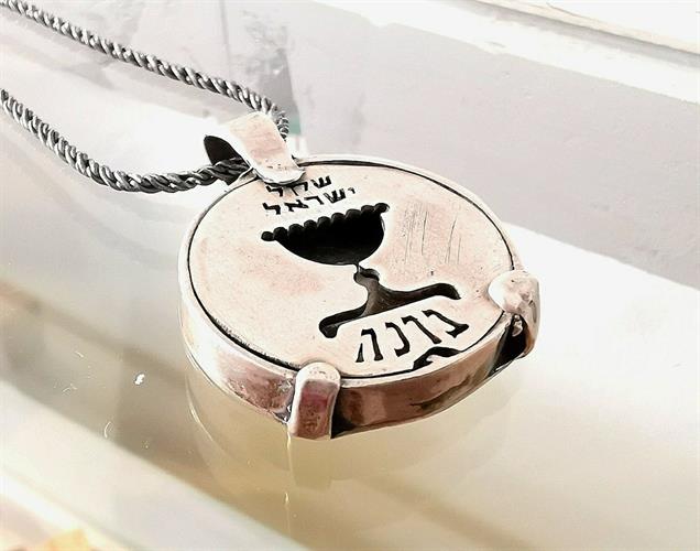 מטבע העצמה, To Be מאת ציפורה אוריה,  תליון כסף עליו חרוט סמל גביע בהשראת השקל הישן בתוספת המילה ברכה