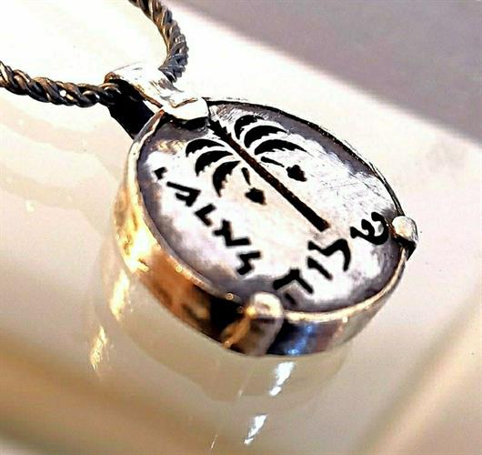 מטבע העצמה, To Be מאת ציפורה אוריה, תליון מטבע כסף עליו חרוט סמל עץ התמר, לקוח ממטבע עברי קדום מימי בר כוכבא ובתוספת המילה שלווה