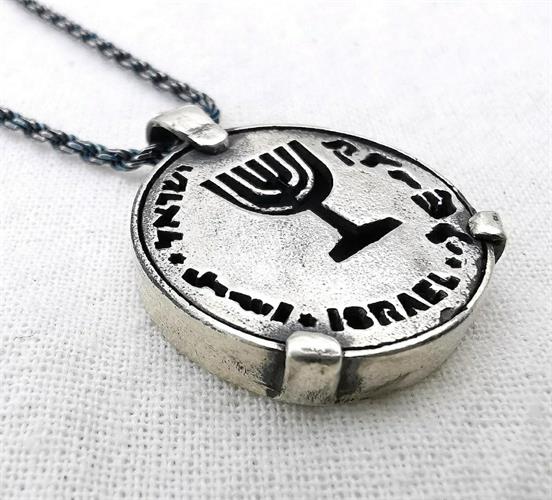 מטבע העצמה, To Be מאת ציפורה אוריה,  תליון כסף בהשראת סמל המנורה בתוספת המילה קדושה