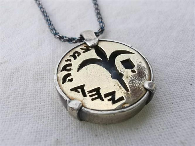 מטבע העצמה, To Be מאת ציפורה אוריה, תליון מטבע זהב וכסף עליו חרוט פרח הלילך בהשראת השקל החדש שהוא סמל קדום מהתקופה הפרסית בתוספת המילה צמיחה.